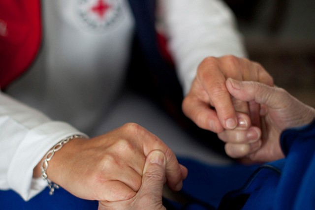 DRK-Mitarbeiterin hält die Hände einer anderen Person