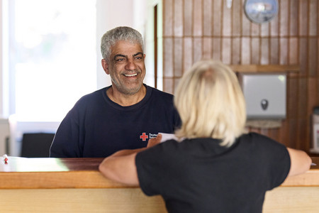 Ein Mitarbeiter des Roten Kreuzes und eine Frau sitzen sich in einer Beratungssituation an einem Tisch gegenüber.