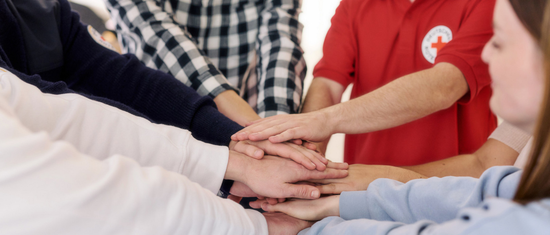 Eine Gruppe steht im Kreis und legt als Team die Hände übereinander