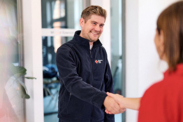 Ein Mitarbeiter begrüßt eine Person mit Handschlag