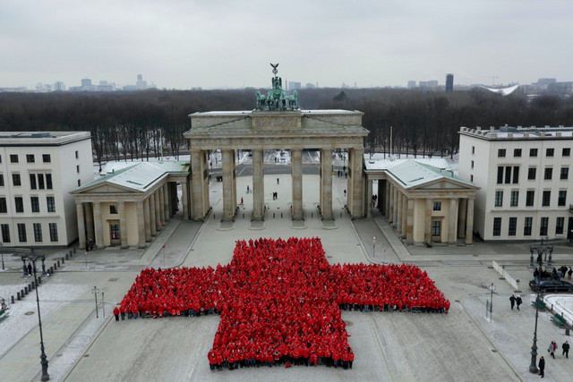 Gruppenbild: Hunderte Rotkreuzler bilden ein rotes Kreuz vor dem Brandenburger Tor